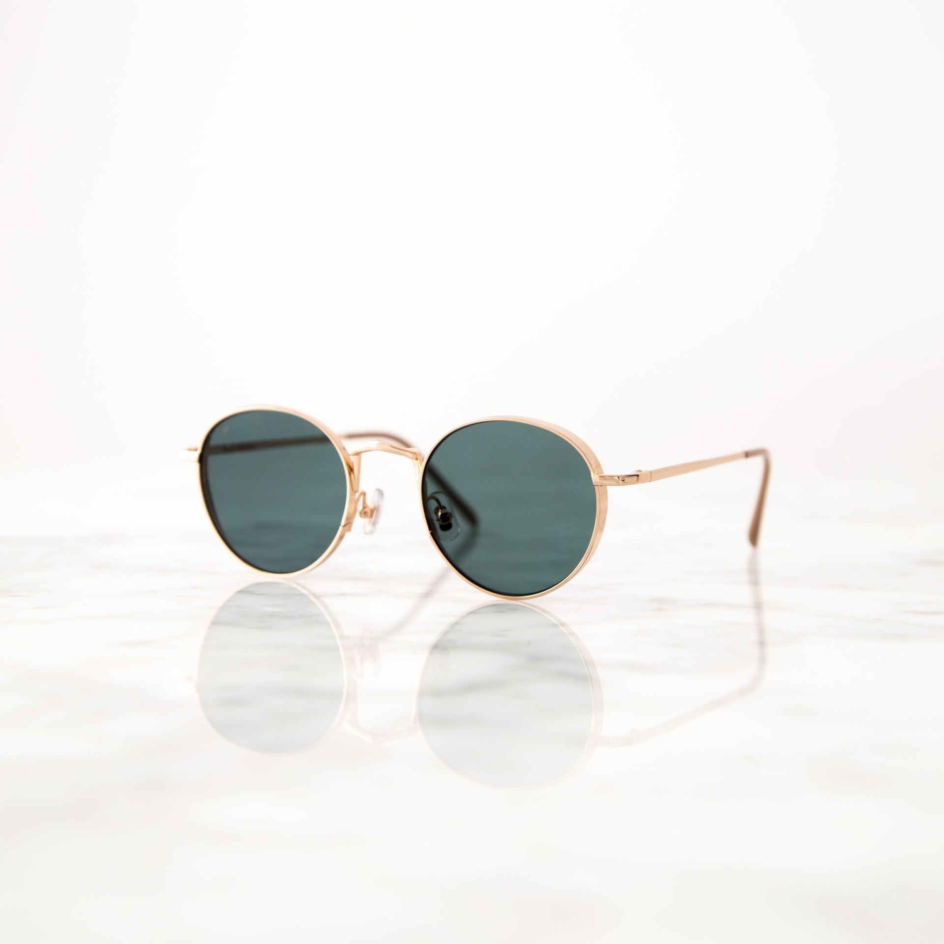 Lunettes solaires Lunettes de soleil à monture dorée sur surface réfléchissante en marbre